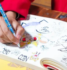 Person drawing with colorful markers on paper.