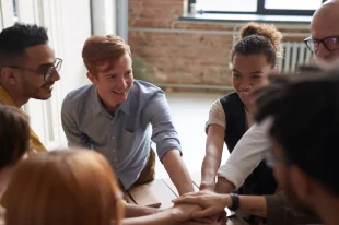 Group of people stacking hands together in teamwork.