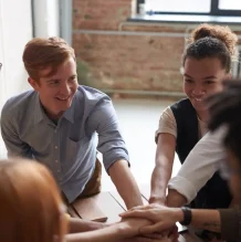 Group of people stacking hands together in teamwork.