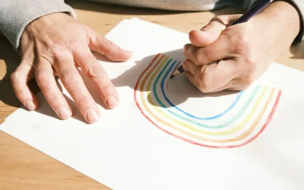 Hand drawing a rainbow with colored pencils.