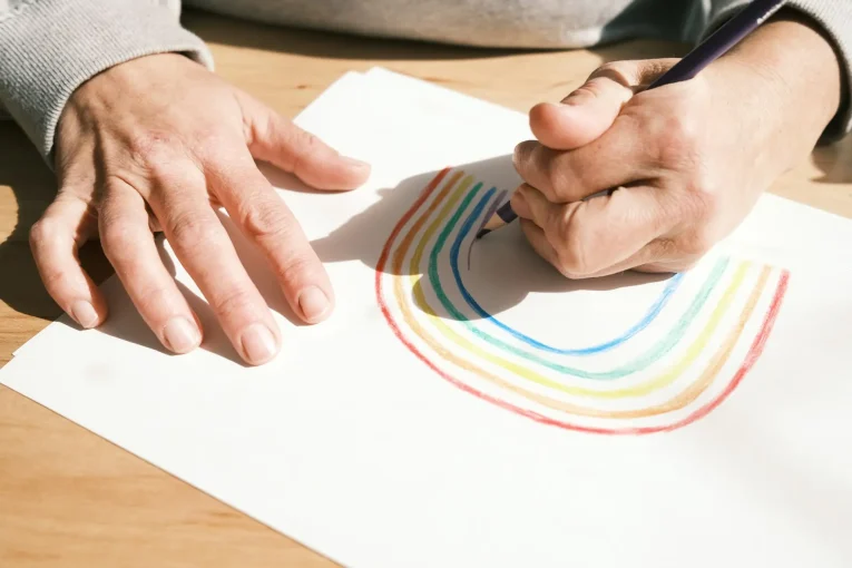 Hand drawing a rainbow with colored pencils.